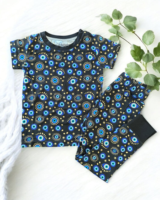 Evil Eye black short sleeve two-piece pajamas for kids, featuring colorful eye patterns and made from soft bamboo fabric.
