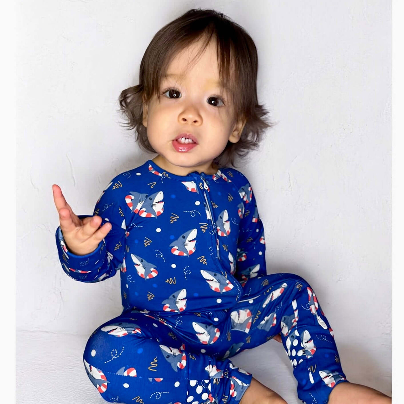 Toddler wearing Shark Floaties Blue Bamboo Zipper Sleeper, showcasing playful shark pattern and vibrant blue color.
