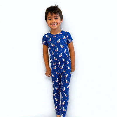 Child wearing Shark Floaties short sleeve two-piece PJ's in blue with fun floatie patterns, smiling happily.