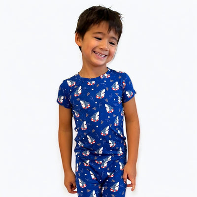 Smiling boy wearing blue Shark Floaties short sleeve two-piece pajamas, showcasing fun shark and floatie pattern.