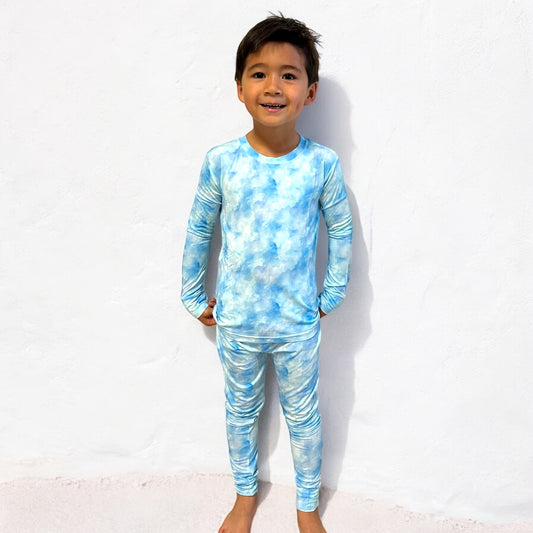 A young boy wearing Blue Skies long sleeve two-piece bamboo pajamas in a blue cloud pattern.