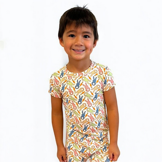 Smiling boy wearing Cottage Bunny short sleeve two-piece pajamas with colorful bunny print.