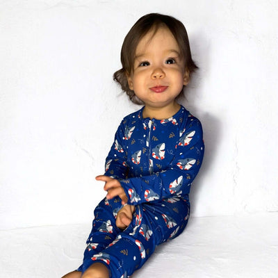 Toddler wearing Shark Floaties blue bamboo zipper sleeper, smiling with playful expression.