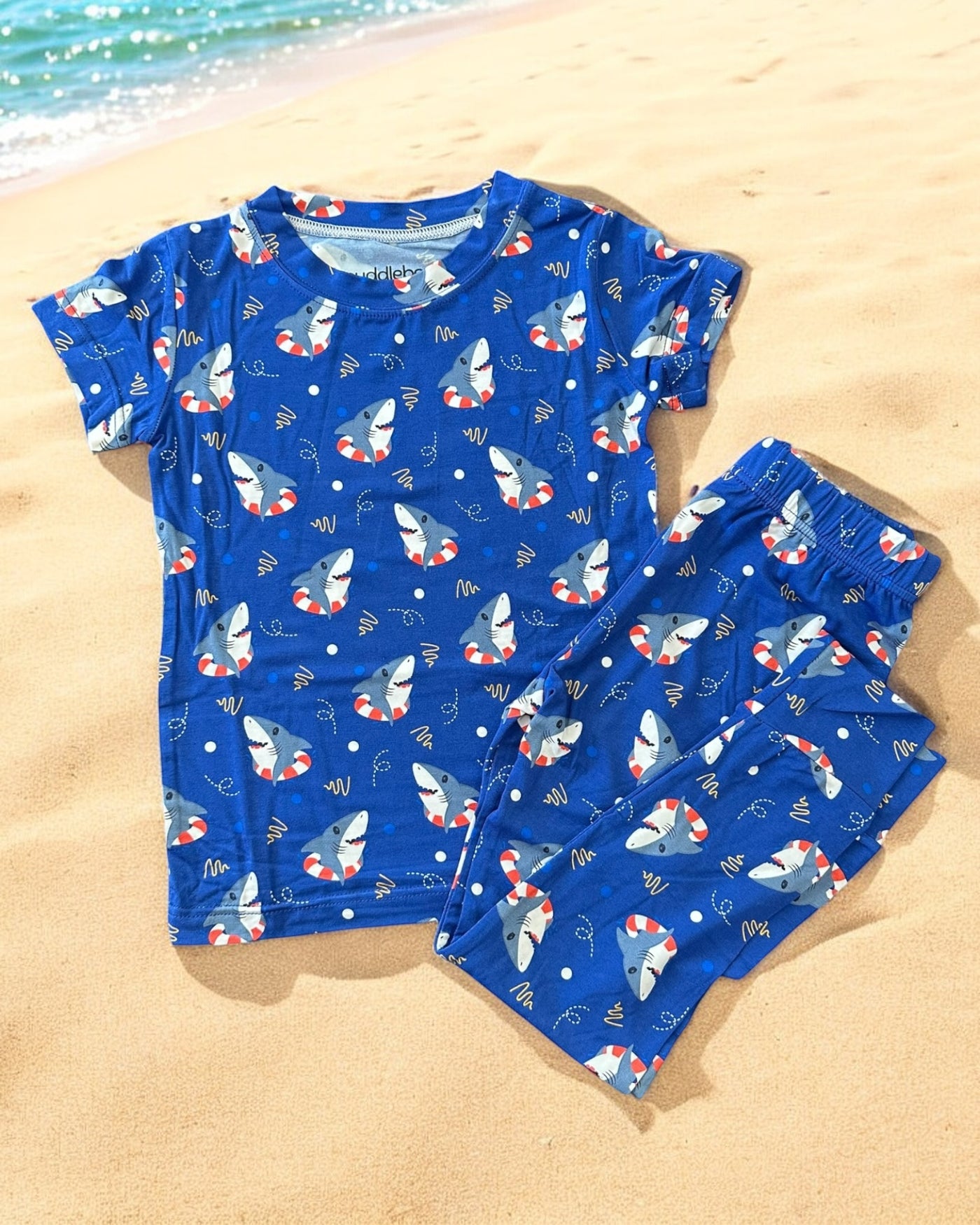 Shark Floaties short sleeve two-piece pajamas for kids, featuring colorful shark prints on a blue background.