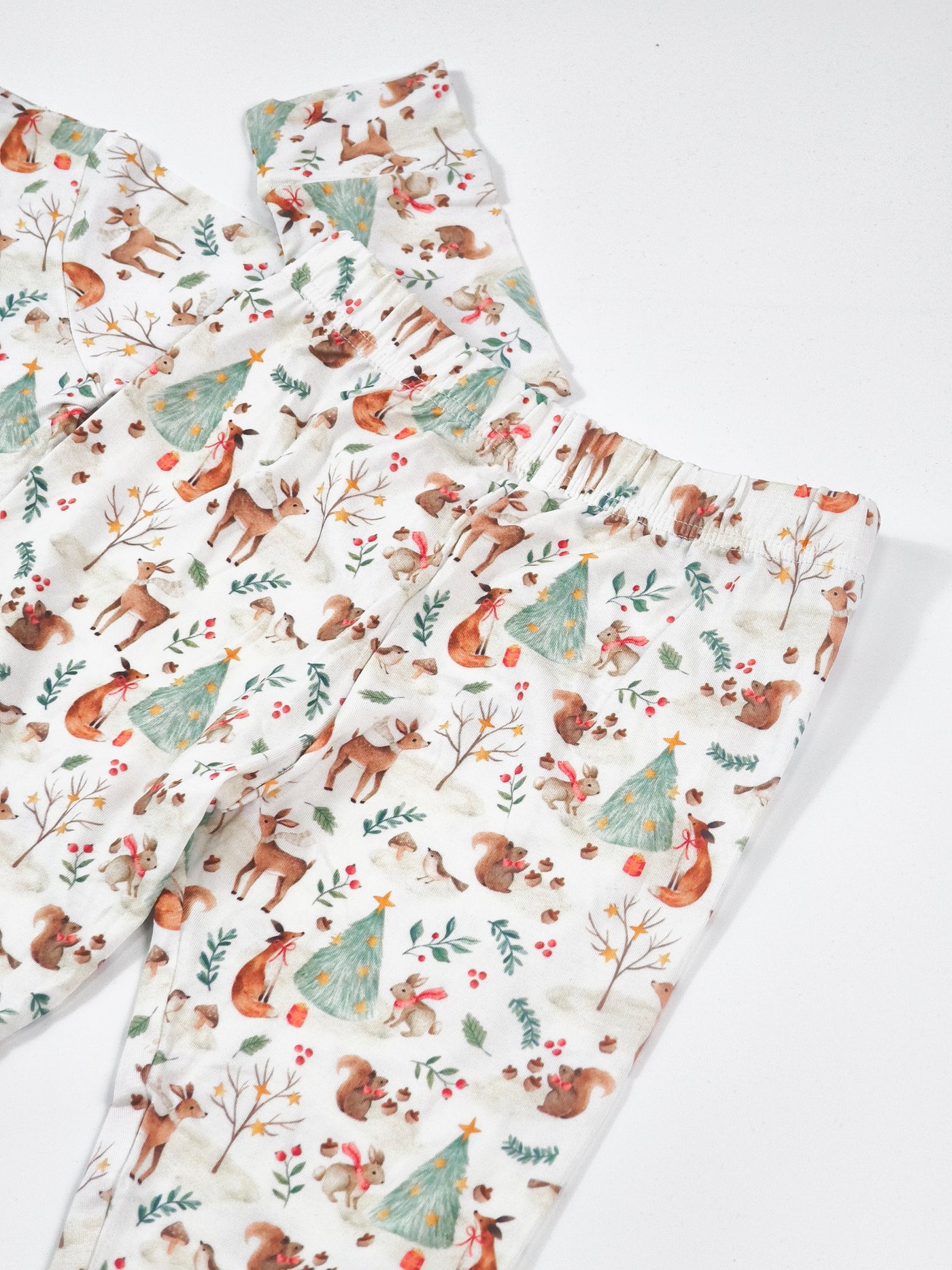 Woodland Christmas Animal print bamboo pajamas for kids featuring trees, deer, and festive motifs.